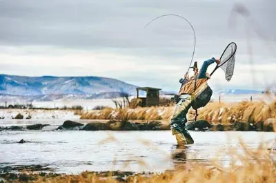a man standing in the water holding a fishing rod at Trout Town Inn in Roscoe