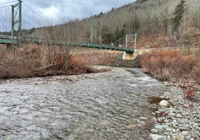 a bridge over a river with rocks and a bridge at Trout Town Inn in Roscoe