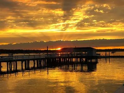 a dock with a house on the water at sunset at Fathoms Hotel & Marina in Port Washington