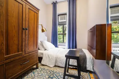 a bedroom with a bed and a dresser and windows at Lamartine Chelsea in New York