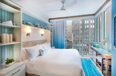 a bedroom with a white bed and a large window at Margaritaville Resort Times Square in New York