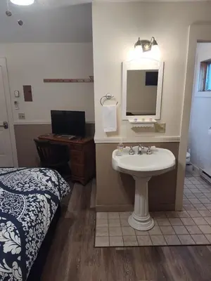 a bathroom with a sink and a bed and a mirror at Doveberry Inn in West Dover