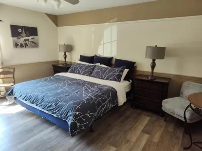 a bedroom with a bed with a blue comforter and a chair at Doveberry Inn in West Dover