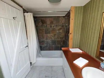 a bathroom with a tub and a sink and a shower at Doveberry Inn in West Dover