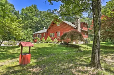 a red barn with a tree and a house at Hike and Ski Log Cabin in East Stroudsburg! in East Stroudsburg