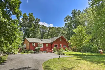 a red house in the middle of a yard at Hike and Ski Log Cabin in East Stroudsburg! in East Stroudsburg