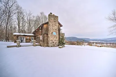 a log cabin with a chimney in the snow at Full Private Home on 32-Acres with Stellar Views! in North Blenheim