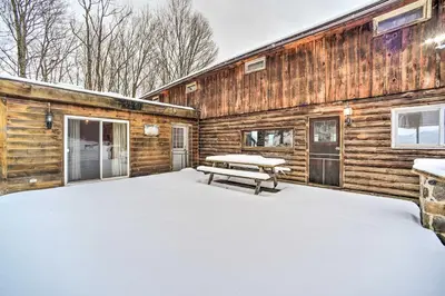 a log cabin with a picnic table in the snow at Full Private Home on 32-Acres with Stellar Views! in North Blenheim