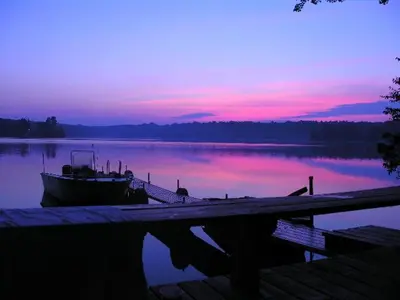 a boat is docked at a dock with a sunset at Cabin Deck House - Formidable Cabin in Laurel Island in East Hampton