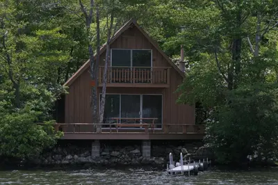 a cabin on the water with a boat in front at Cabin Deck House - Formidable Cabin in Laurel Island in East Hampton
