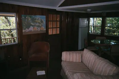 a living room with a couch and a table and windows at Cabin Deck House - Formidable Cabin in Laurel Island in East Hampton