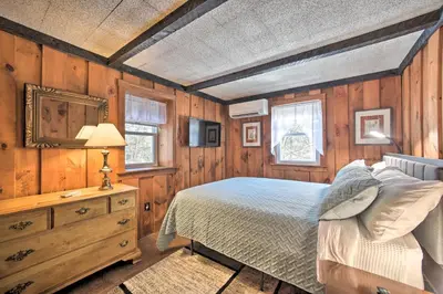 a bedroom with a bed and a wooden wall at Cozy Great Barrington Home about 1 Mi to Ski Resort! in Great Barrington