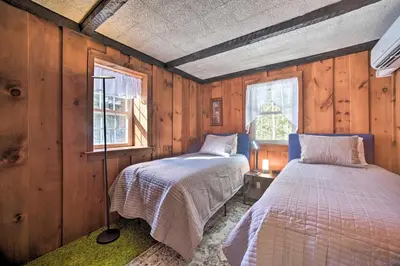 two beds in a room with wooden walls at Cozy Great Barrington Home about 1 Mi to Ski Resort! in Great Barrington