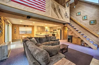 a living room with a large couch and a staircase at Cozy Mountain Retreat with Deck about 3 Mi to Mount Snow in West Dover