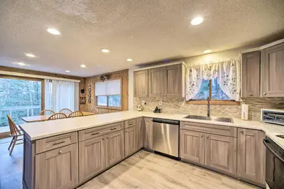 a kitchen with wooden cabinets and a large window at Cozy Mountain Retreat with Deck about 3 Mi to Mount Snow in West Dover