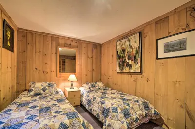 two beds in a room with wood paneling at Cozy Mountain Retreat with Deck about 3 Mi to Mount Snow in West Dover