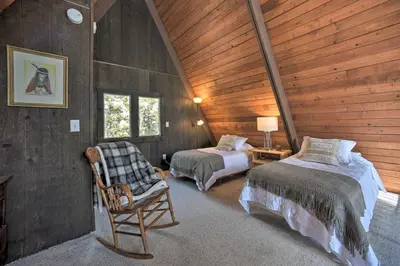 a bedroom with two beds and a chair in a cabin at Cozy A-Frame Cabin with Pool Table 8 Mi to Mt Snow! in Wilmington