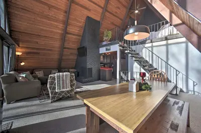 a living room with a wooden table and a fireplace at Cozy A-Frame Cabin with Pool Table 8 Mi to Mt Snow! in Wilmington