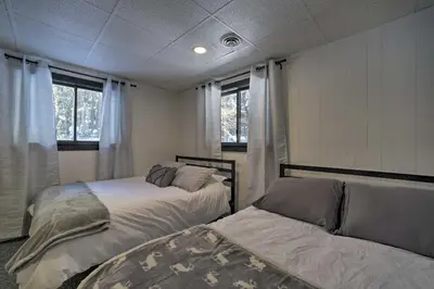 a bedroom with two beds and two windows at Cozy A-Frame Cabin with Pool Table 8 Mi to Mt Snow! in Wilmington