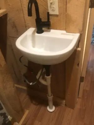 a white sink in the corner of a bathroom at The HideAway Tiny Cabin in East Durham