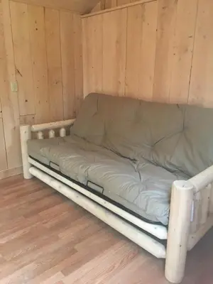 a bed in a room with wooden walls at The HideAway Tiny Cabin in East Durham