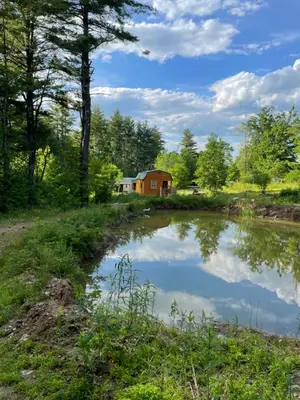 a pond with a barn in the background at The HideAway Tiny Cabin in East Durham