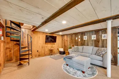 a living room with a couch and a spiral staircase at Lakefront Granby Escape with Private Dock and Kayaks! in Granby