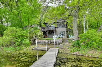 a house with a wooden bridge over a pond at Lakefront Granby Escape with Private Dock and Kayaks! in Granby