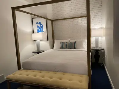 a bedroom with a canopy bed with a bench at The Argus Hotel & Cocktail Lounge in Albany