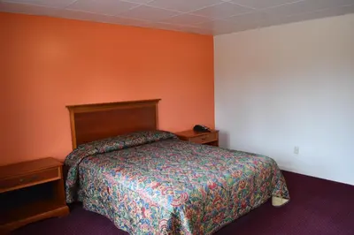 a bedroom with a bed and an orange wall at PLYMOUTH MOTOR LODGE in Terryville