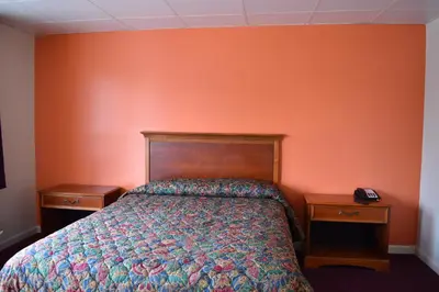 a bedroom with a bed and two night stands at PLYMOUTH MOTOR LODGE in Terryville
