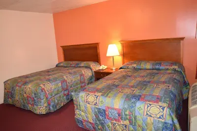 two beds in a hotel room with orange walls at PLYMOUTH MOTOR LODGE in Terryville