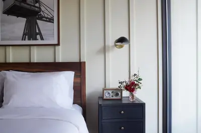 a bedroom with a bed and a nightstand with a clock at Hutton Brickyards Riverfront Hotel & Venue in Kingston