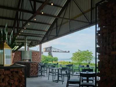 a patio with tables and chairs in a building at Hutton Brickyards Riverfront Hotel & Venue in Kingston