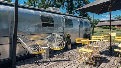 a group of chairs and tables and an umbrella next to a trailer at Hutton Brickyards Riverfront Hotel & Venue in Kingston