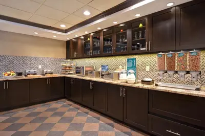 a large kitchen with dark brown cabinets and counter tops at Homewood Suites by Hilton Hartford / Southington CT in Southington
