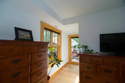 a living room with a dresser and a flat screen tv at Too Good AKA 2 Goodrich St in Stockbridge