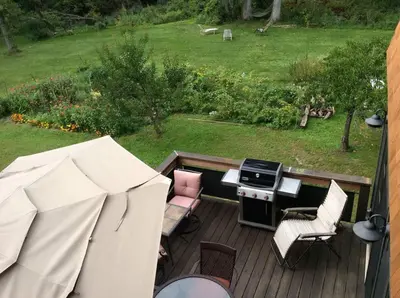 a patio with a grill and chairs on a deck at Too Good AKA 2 Goodrich St in Stockbridge