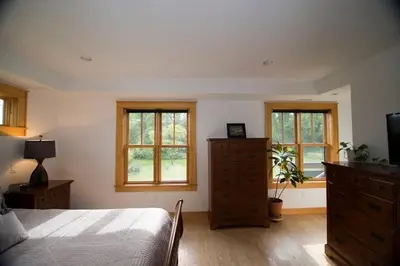 a bedroom with a bed and a dresser and windows at Too Good AKA 2 Goodrich St in Stockbridge