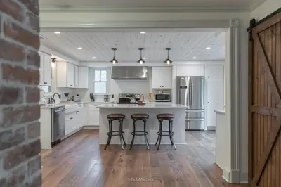 a kitchen with white cabinets and a island with bar stools at Restored 1881 Farm House in Lenox