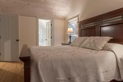 a bedroom with a large bed with a wooden headboard at Restored 1881 Farm House in Lenox