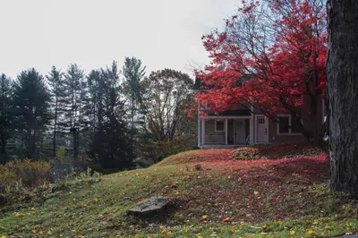 a house on a hill with a tree with red leaves at Restored 1881 Farm House in Lenox