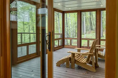 a wooden porch with a rocking chair and windows at Private Home Overlooking Stevens Lake in Great Barrington