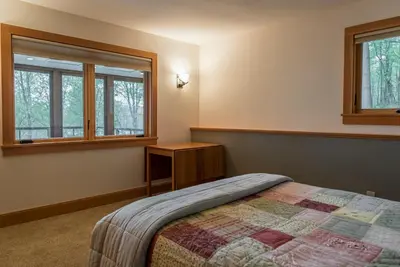 a bedroom with a bed and two windows at Private Home Overlooking Stevens Lake in Great Barrington
