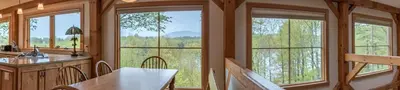 a kitchen with large windows and a table with chairs at Private Home Overlooking Stevens Lake in Great Barrington