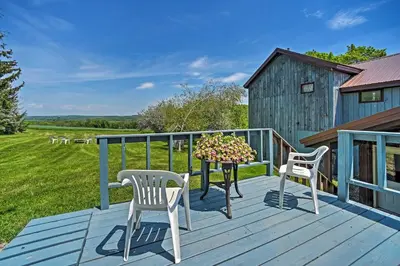 a deck with two chairs and a table with flowers at Country Escape with Sauna, 10 Mi to Cooperstown in Richfield Springs