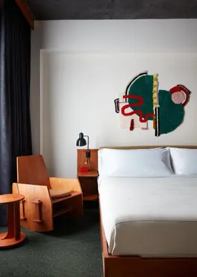 a bedroom with a bed and a chair and a table at Ace Hotel Brooklyn in Brooklyn