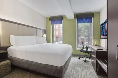 a large white bed in a room with a desk and window at Hotel 1200 in Brooklyn