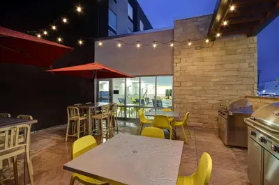 a rooftop patio with tables and chairs and lights at Home2 Suites East Hanover, NJ in East Hanover