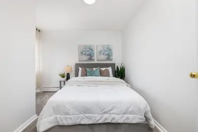 a white bedroom with a large bed with white sheets at Beautiful 3 bedroom Condo in Hartford! in Hartford